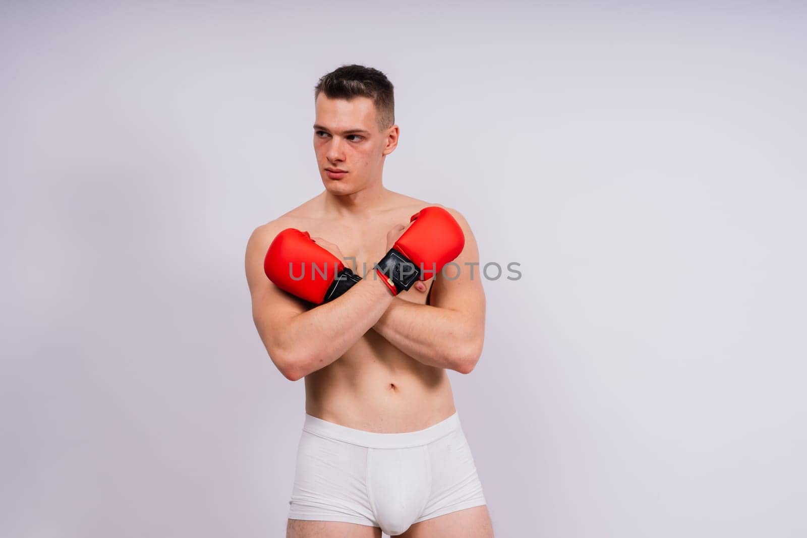 Bodybuilders boxing gloves on a white background and white pants athlete model