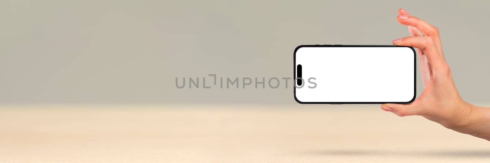 Phone in hand on a white background. A woman's hand holds a new modern phone in her hand on a white background with a blank white screen