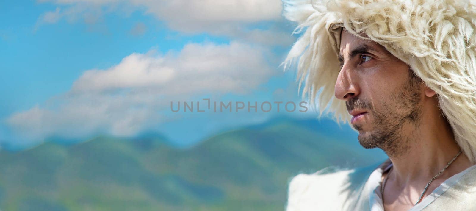 A Georgian man in a hat against the background of mountains and the sky. Selective focus. People.