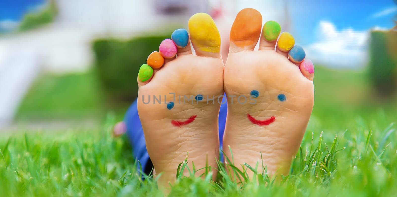 Feet of a child on the grass with a painted smile. Selection focus. Kid.