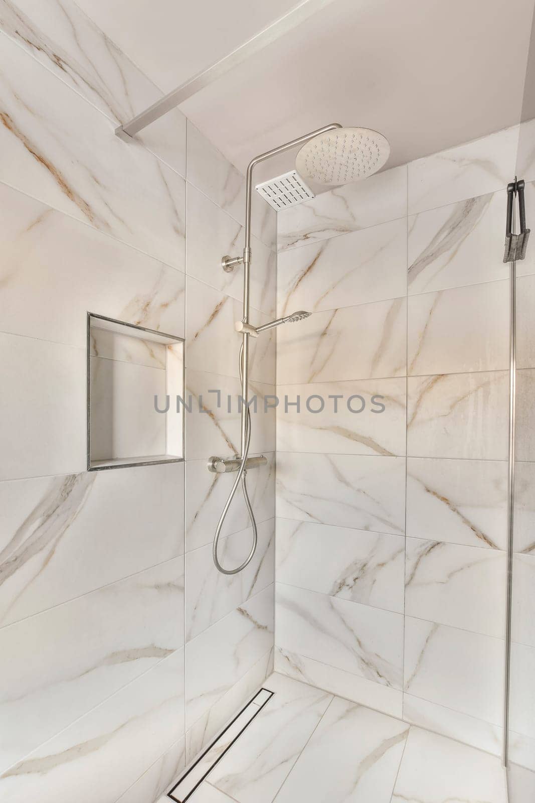 a bathroom with marble walls and white tiles on the shower wall, there is an overhead shower head in the corner