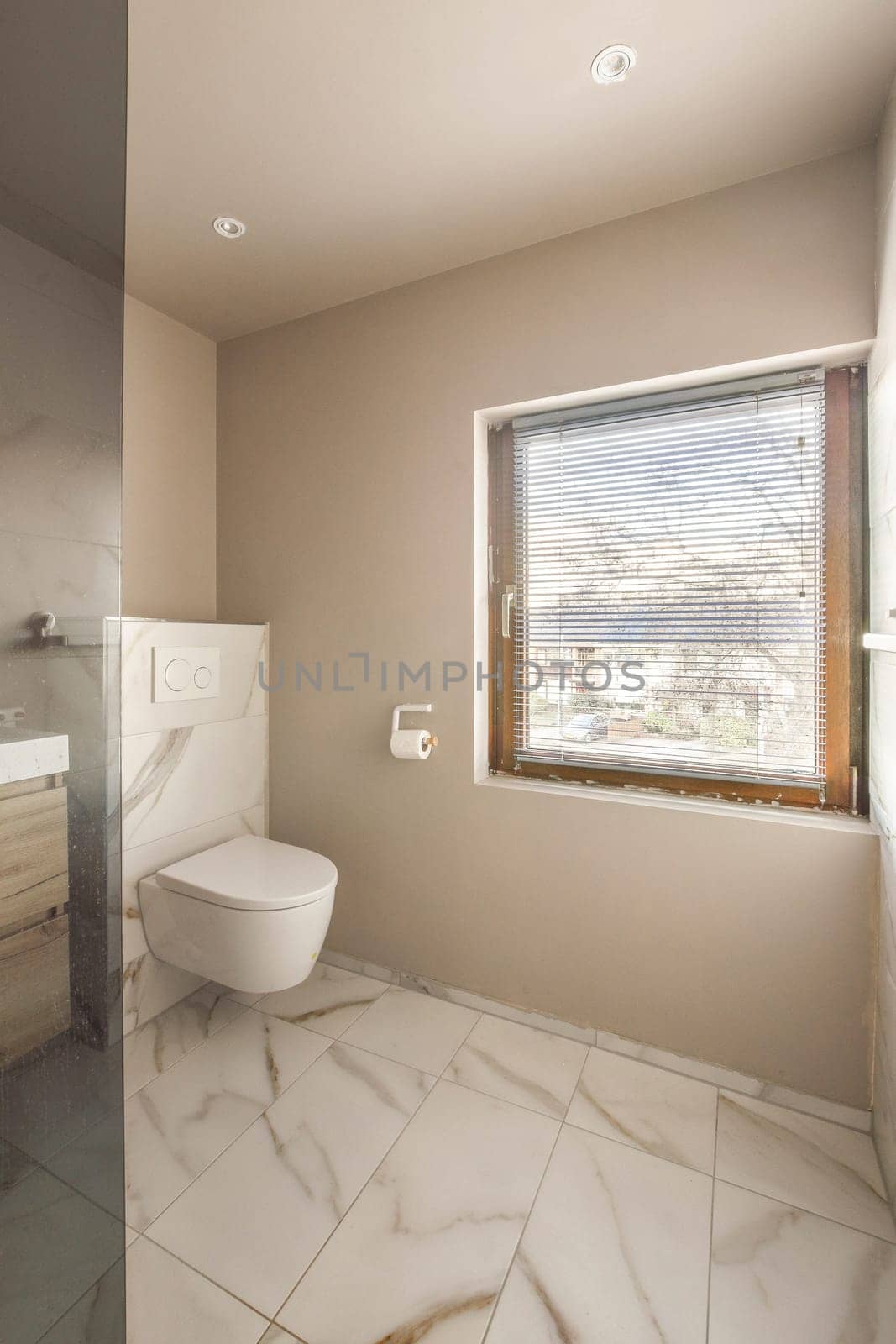 a bathroom with a toilet and sink in the corner, looking out to the outside from behind it is an open window