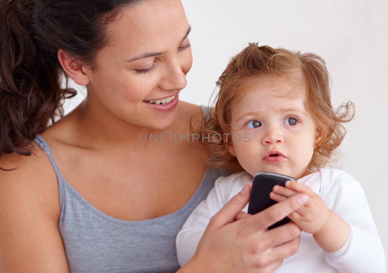 I love mommys cellphone. An adorable baby girl holding her mothers mobile phone. by YuriArcurs
