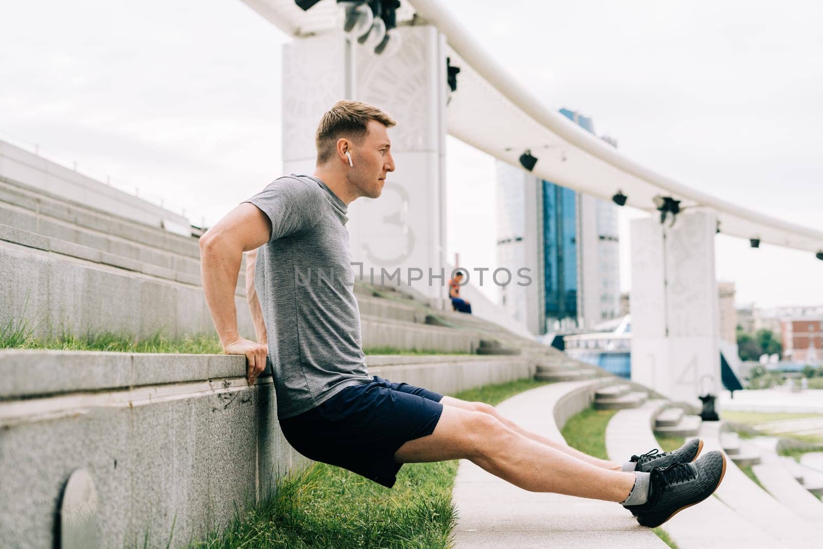 Young man has fitness workout. Male athlete does abs exercise, sport and training outdoor and stands in plank. People sport and healthy lifestyle concept.