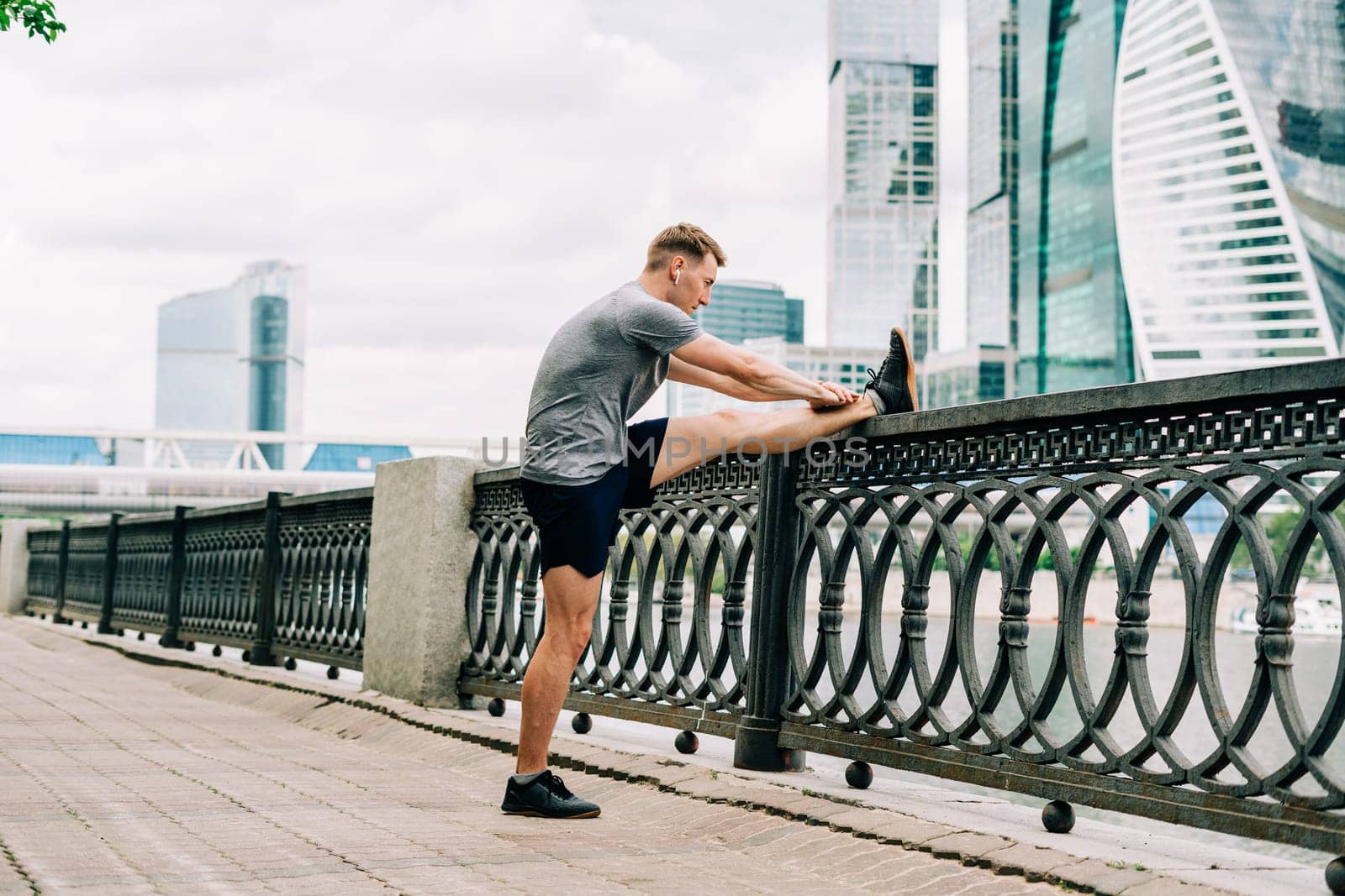 Young fitness man runner stretching legs before exercise run outdoors in city urban street. Healthy lifestyle and sport concept.