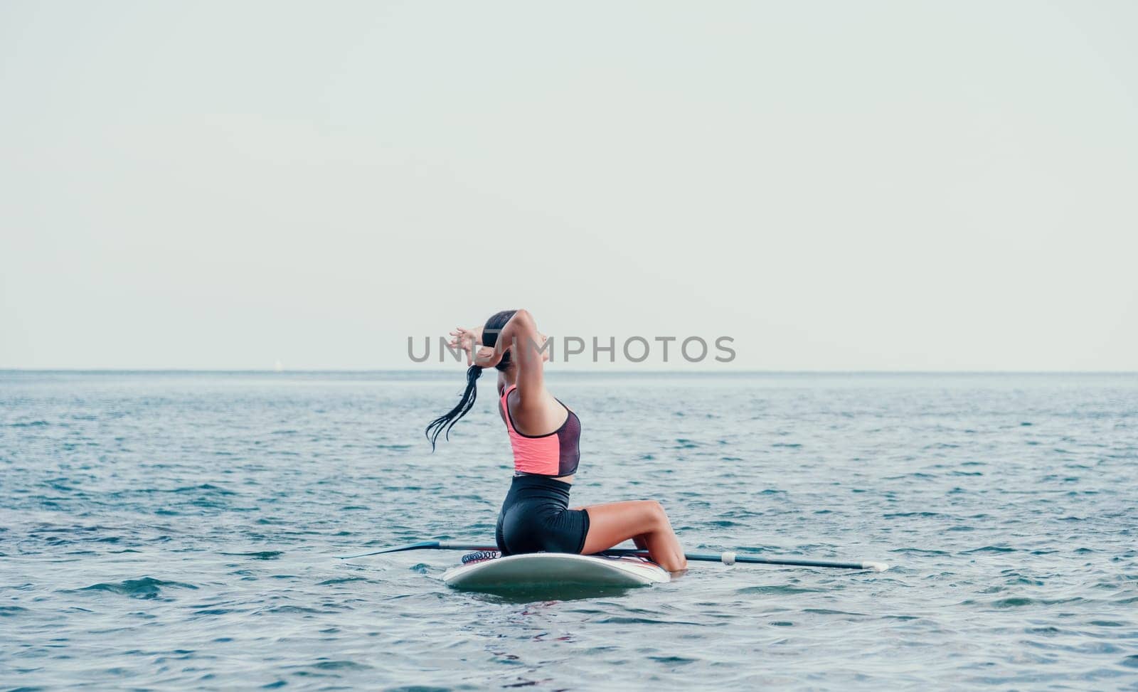 Sea woman sup. Silhouette of happy young woman in pink bikini, surfing on SUP board, confident paddling through water surface. Idyllic sunset. Active lifestyle at sea or river. Slow motion