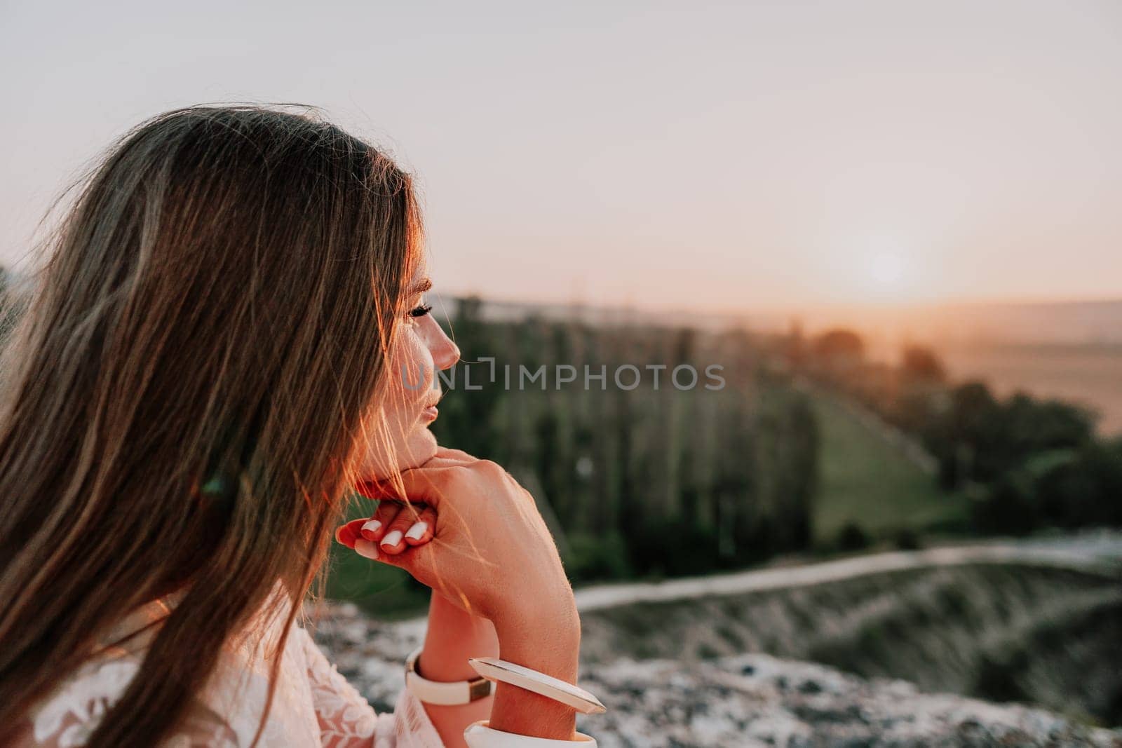 Romantic beautiful bride in white dress posing with sea and mountains in background. Stylish bride standing back on beautiful landscape of sea and mountains on sunset