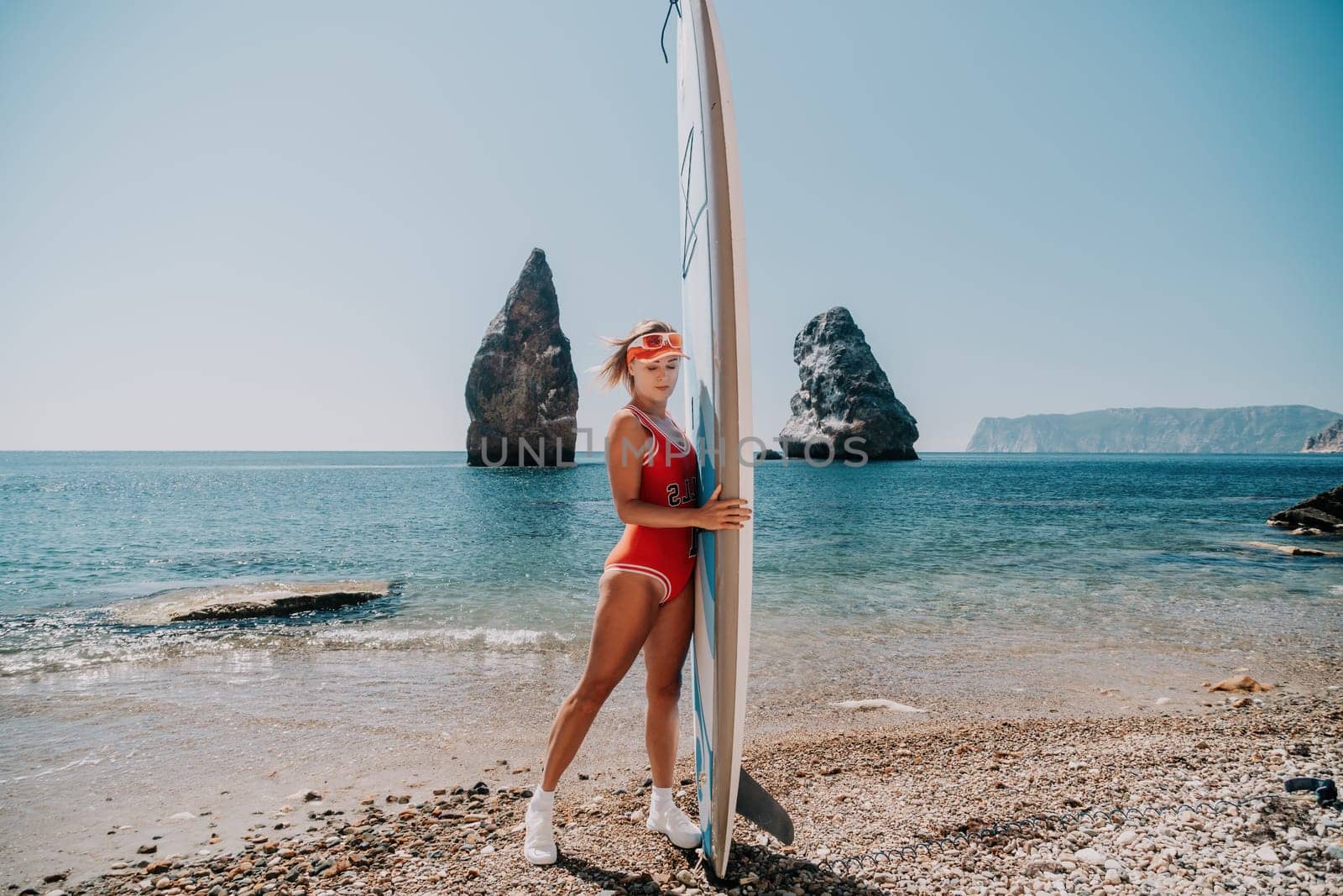 Close up shot of beautiful young caucasian woman with black hair and freckles looking at camera and smiling. Cute woman portrait in a pink bikini posing on a volcanic rock high above the sea