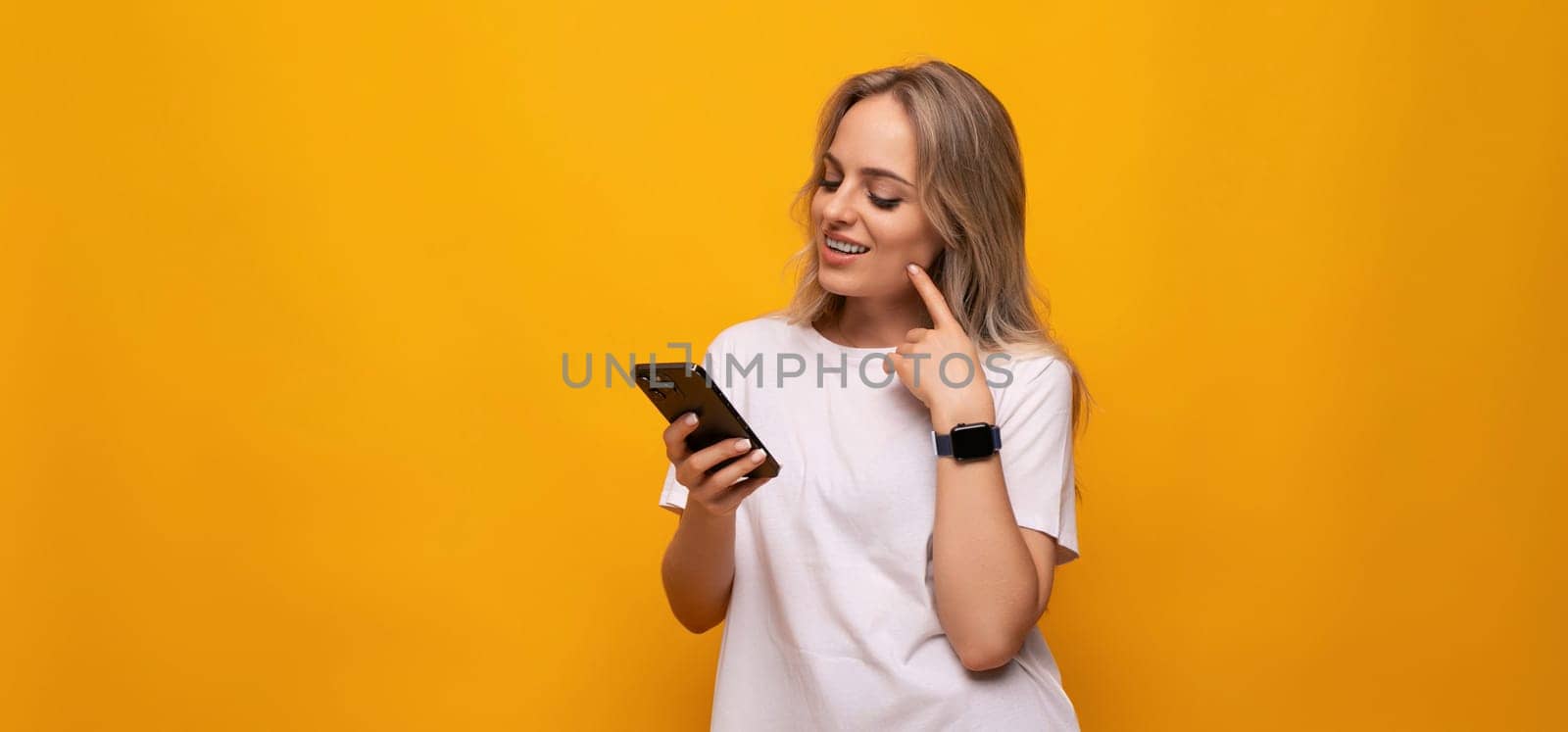 a woman with a smartphone in her hands chooses purchases on a yellow background by TRMK