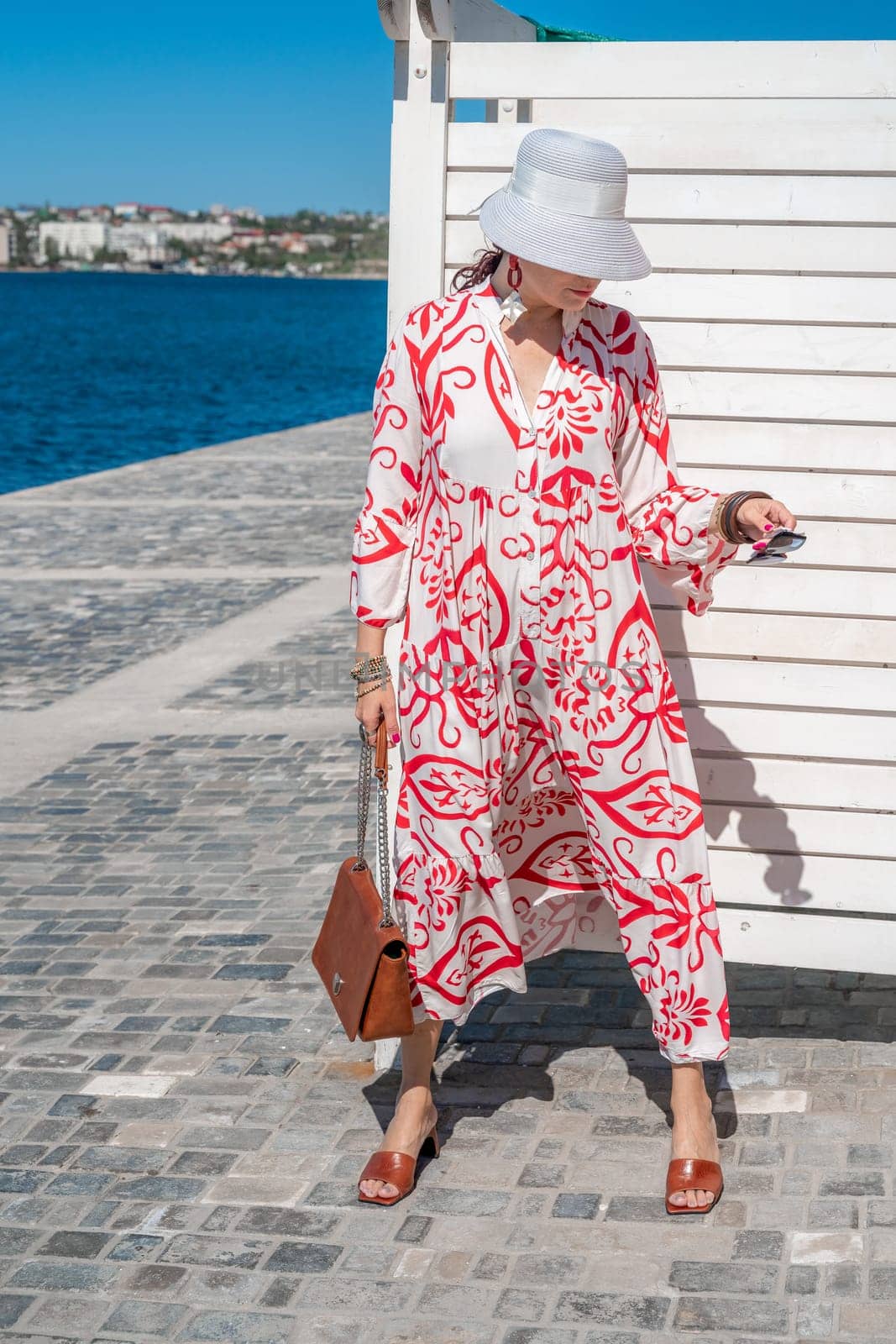 woman in a hat and dress enjoys the blue sea and summer. Welcome summer