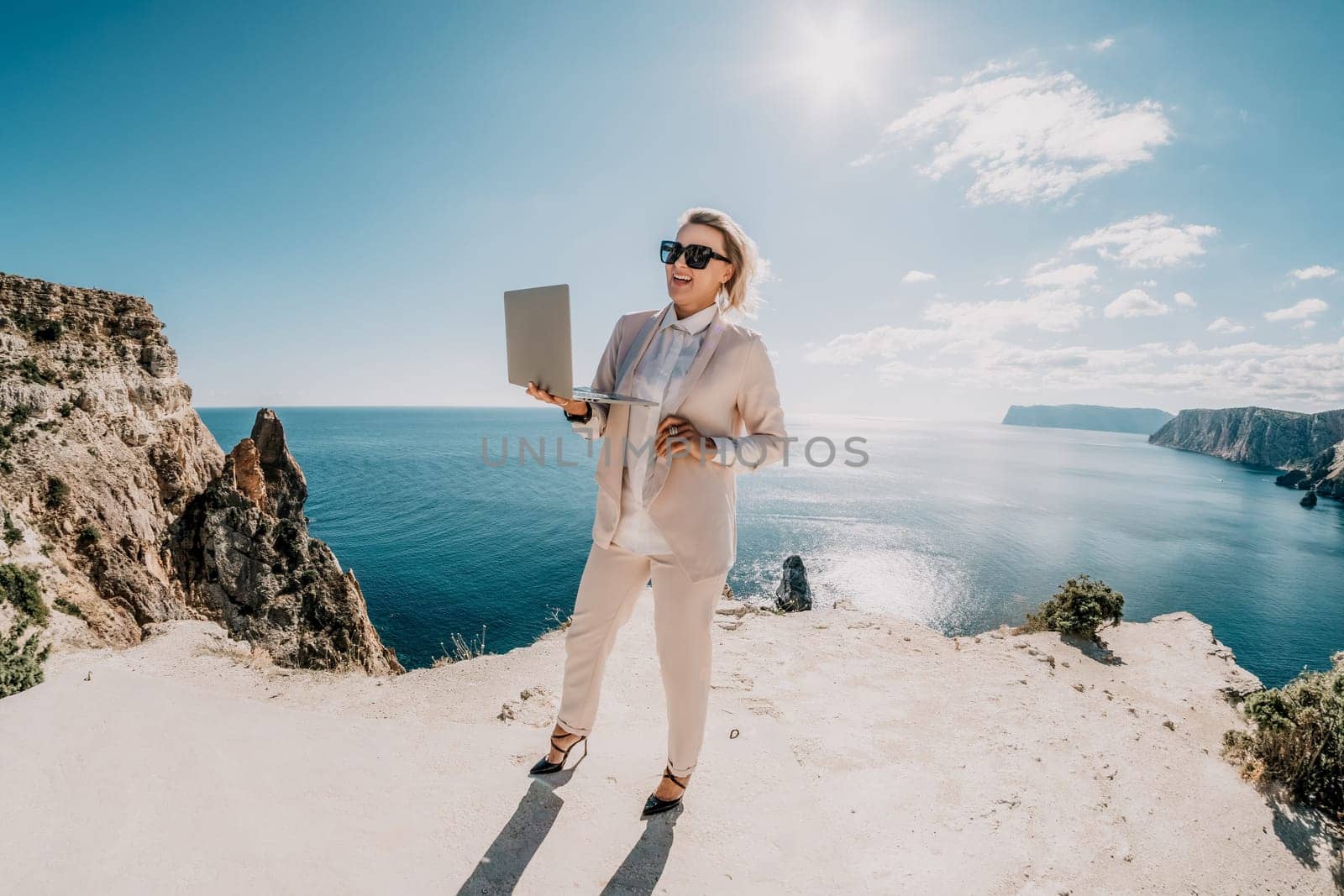 Digital nomad, Business woman working on laptop by the sea. Pretty lady typing on computer by the sea at sunset, makes a business transaction online from a distance. Freelance, remote work on vacation by panophotograph