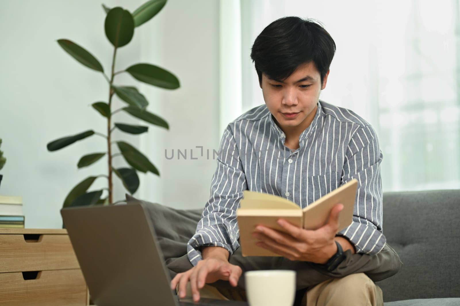 Handsome asian man freelancer using laptop and checking his working schedule plan on notebook.