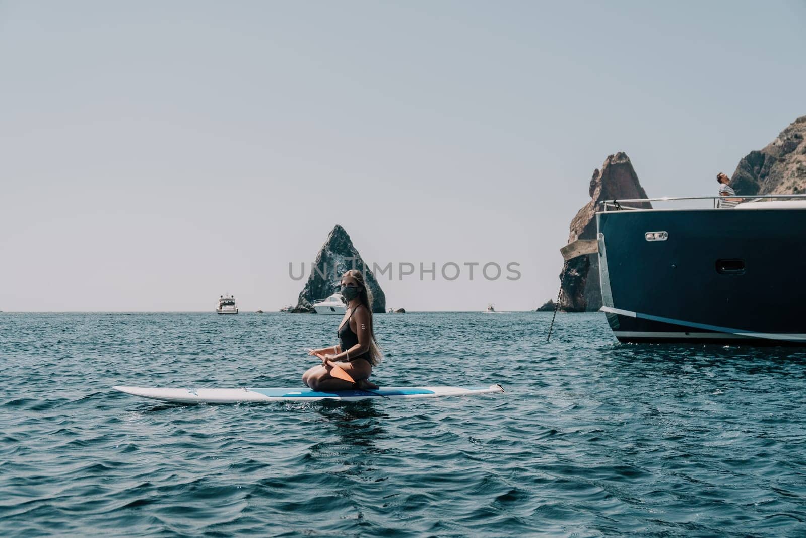 Woman sea sup. Close up portrait of happy young caucasian woman with long hair looking at camera and smiling. Cute woman portrait in bikini posing on sup board in the sea by panophotograph