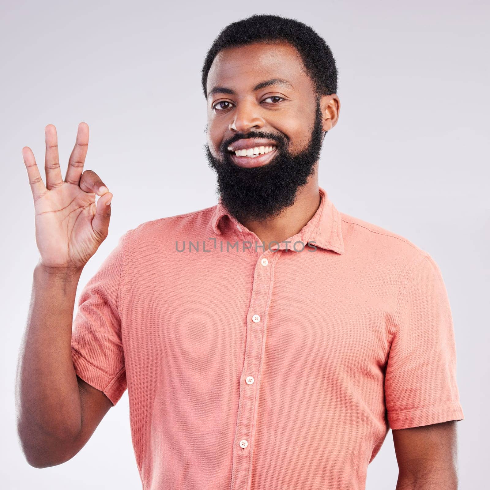 Portrait, perfect and hand gesture with a black man in studio on a gray background to say magnifique. Emoji, communication and okay with a happy or handsome young male speaking in sign language.