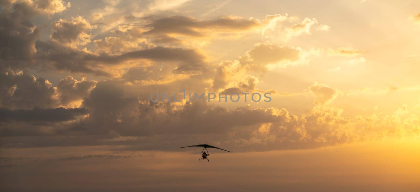 Propeller plane flies in the sunset sky. Banner, A small private hang-glider in a cloudy sky