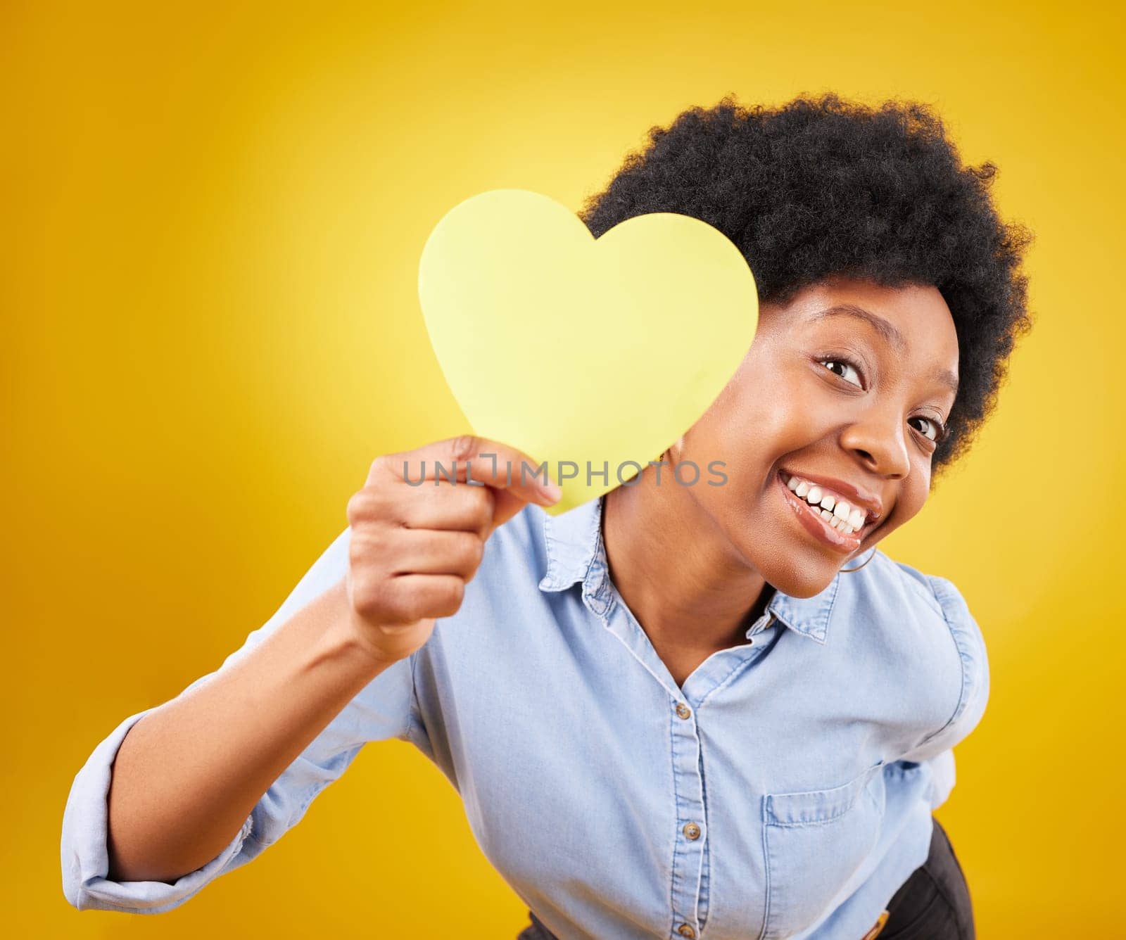 Portrait, heart and social media with a black woman in studio on a yellow background for love or affection. Emoji, shape and romance with an attractive young female feeling excited for valentines day.