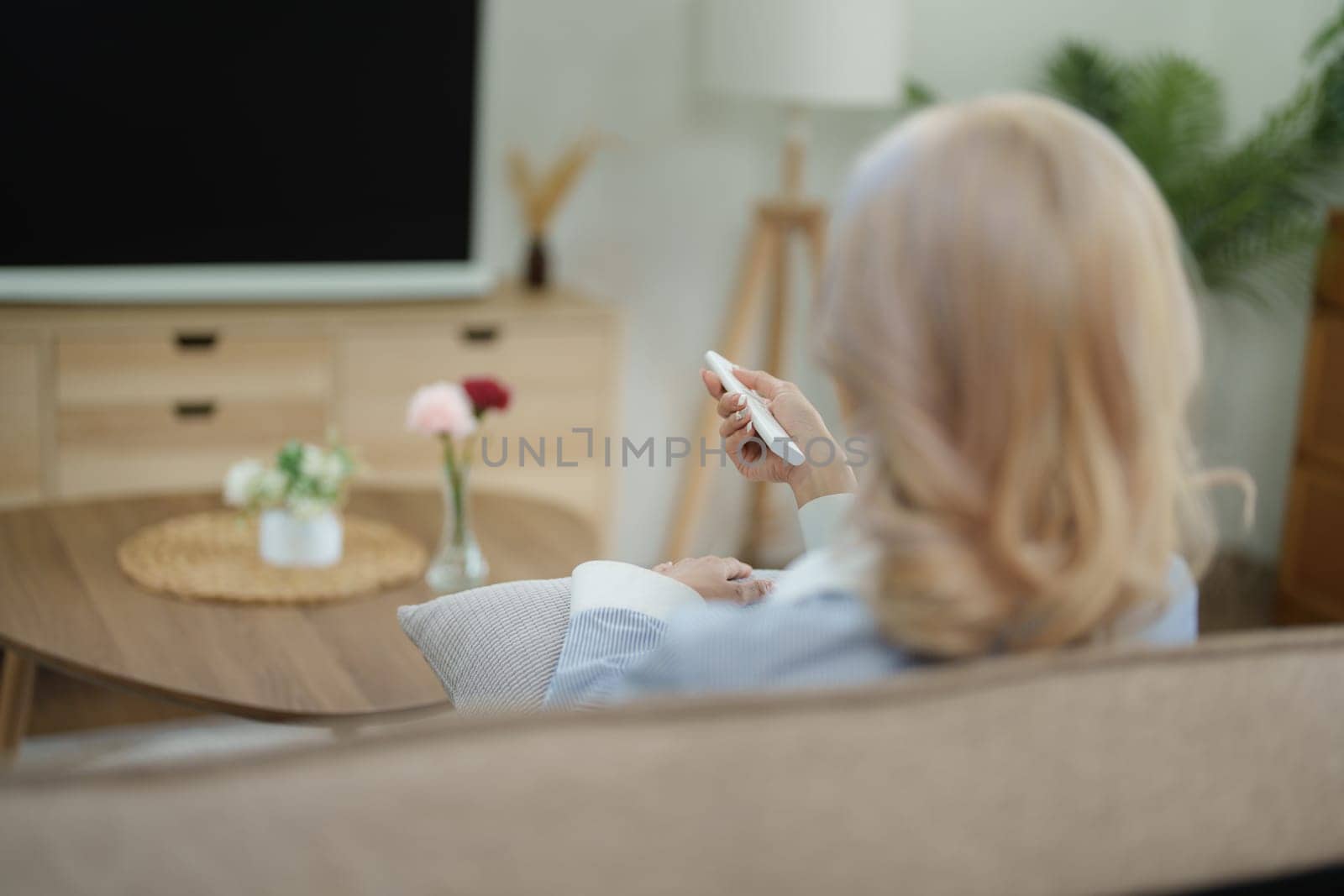 Portrait of a beautiful Asian woman relaxing at home watching television by Manastrong