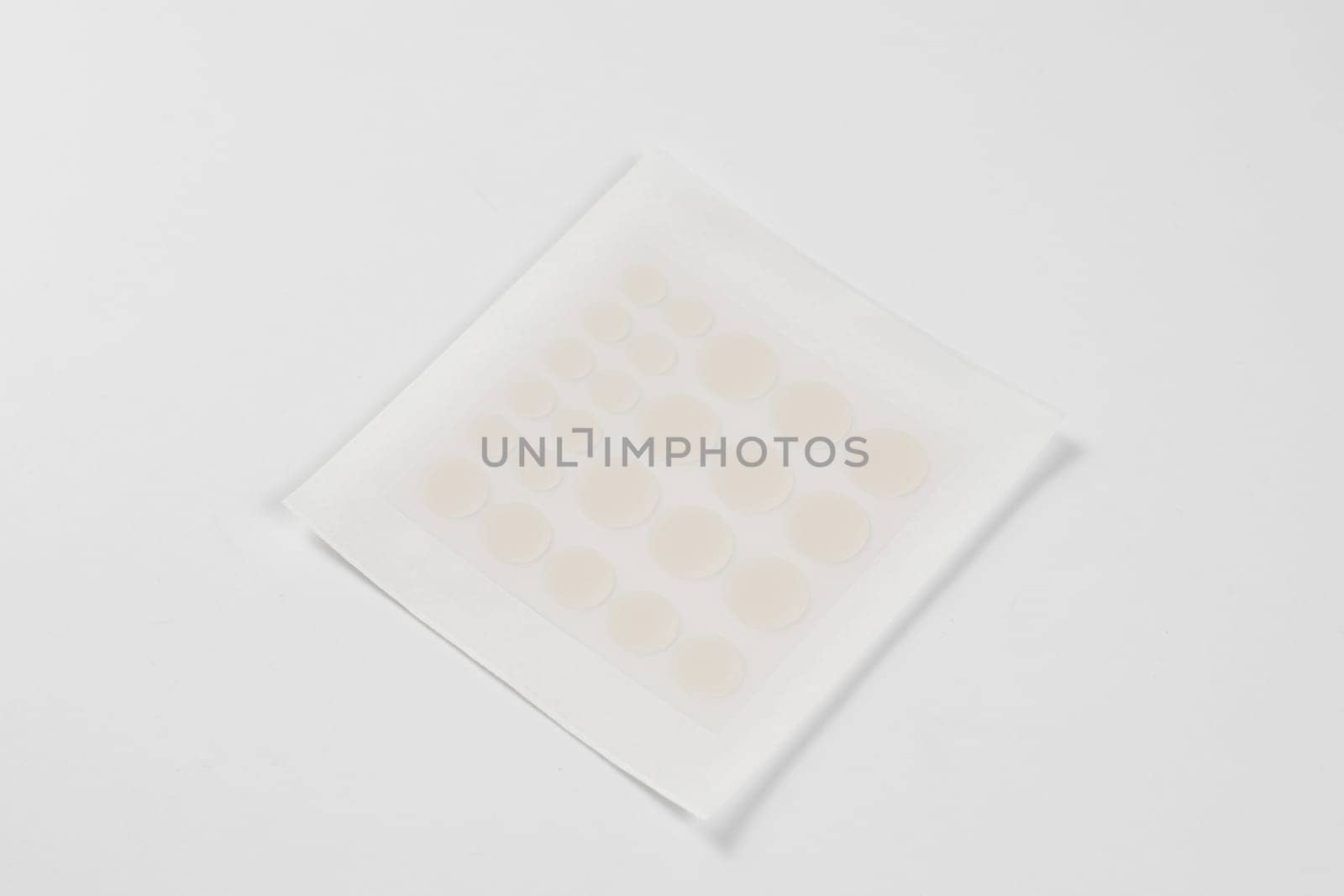 Set of round acne patches on white background. Close-up acne patch facial rejuvenation. Facial cleansing cosmetology. by Rabizo