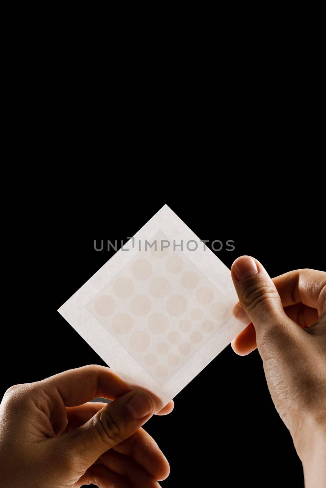 Close-up acne patch for facial rejuvenation. Set of round patches for acne in hands on black background. Facial cleansing cosmetology. by Rabizo