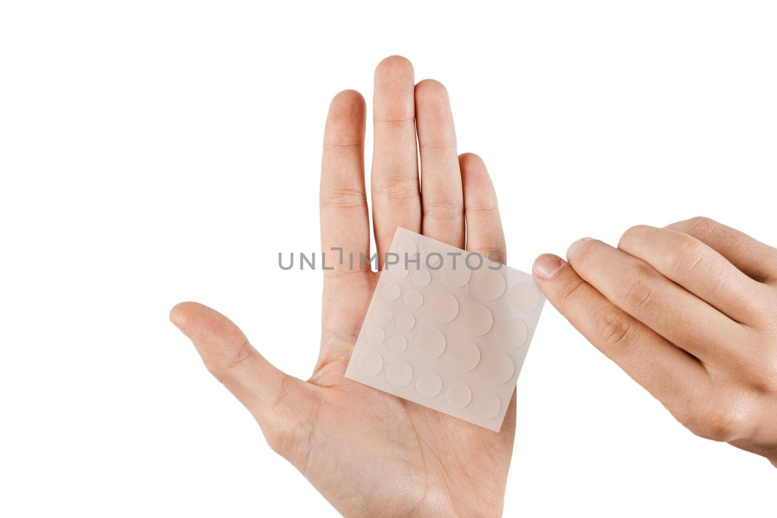 Acne patches for treatment of pimple and rosacea close-up. Facial rejuvenation cleansing cosmetology. Set of round patches for acne in hands on white background. by Rabizo
