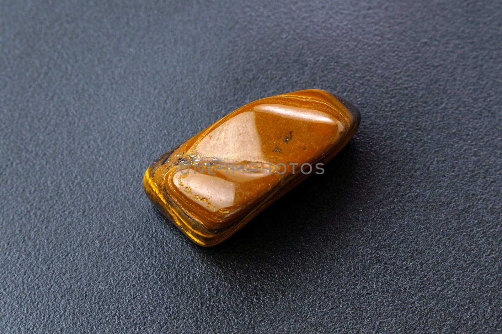 Natural mineral gem stone Tiger eye gemstone on black background close-up.