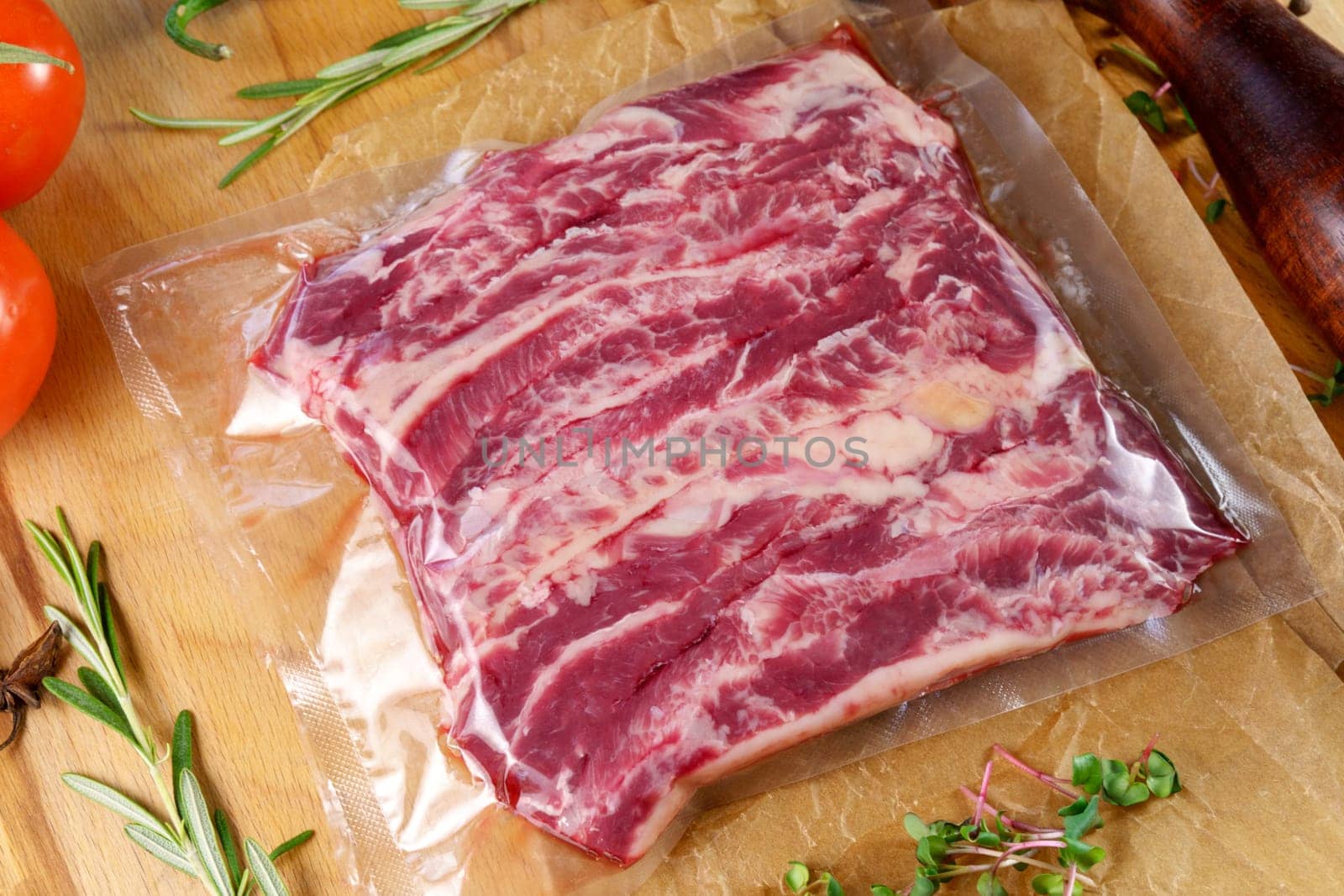 Vacuum packed meat, on a wooden board, steak. Top view. Various spices