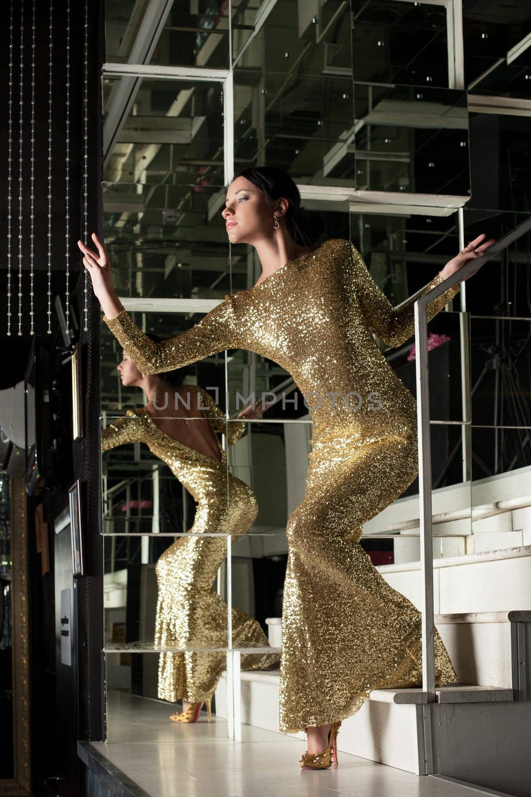 Full length portrait of young woman in fasgion gold dress on stairs