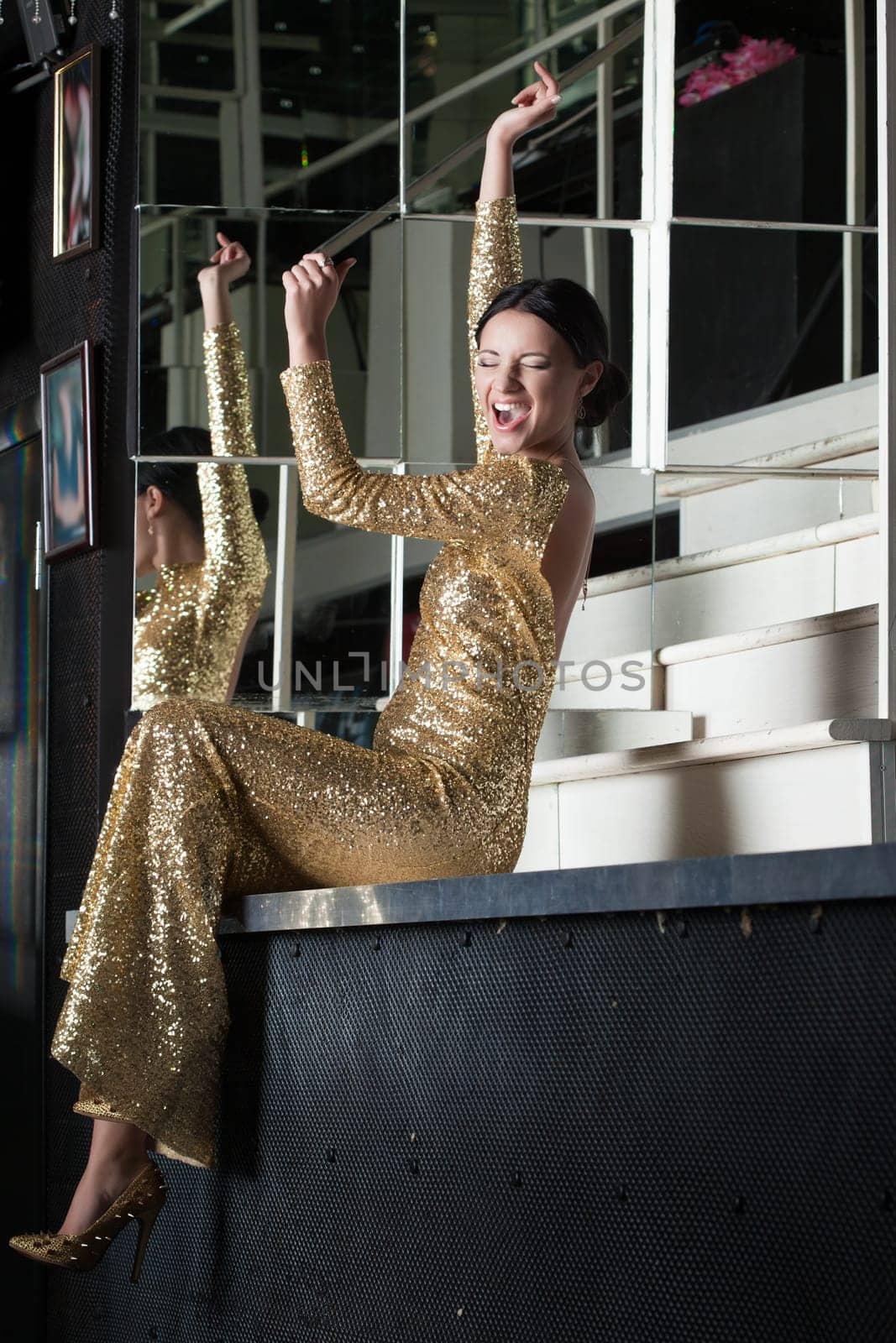 Beauty woman in sexy gold dress have fun on bar table