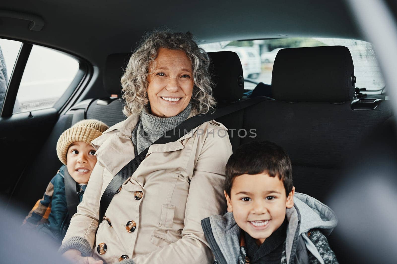 Portrait, car ride and grandmother relax with children or grandchildren while travel or on a road trip in the backseat. Bonding, happy and grandma traveling with kids or grandkids on a journey.