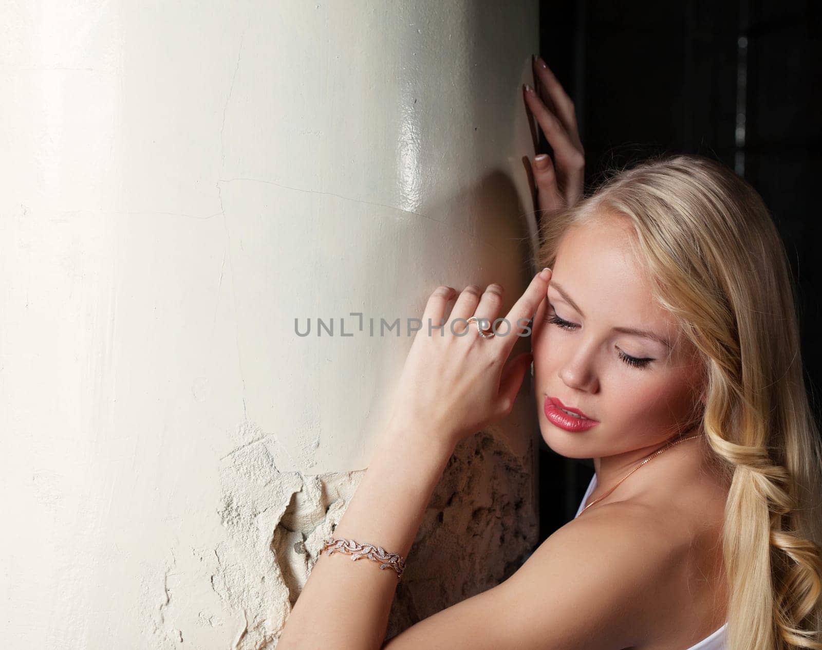Portrait of charming blonde posing leaning column