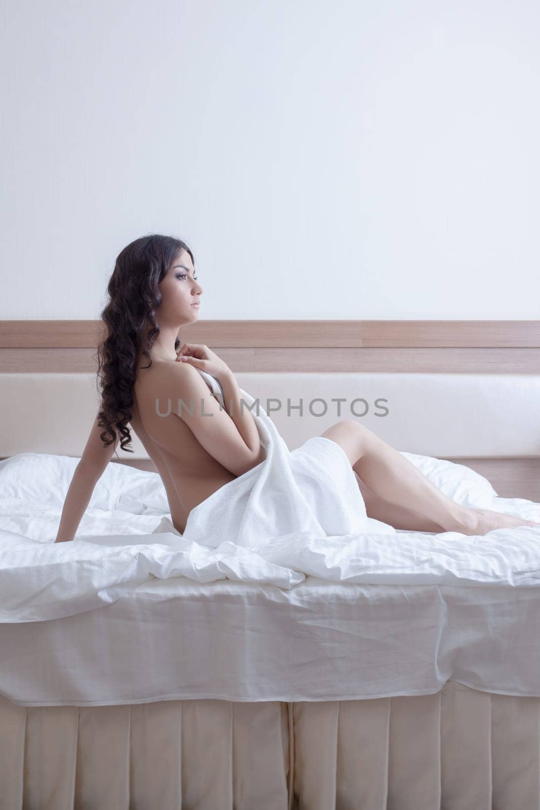Portrait of beautiful brunette woman in towel on bed