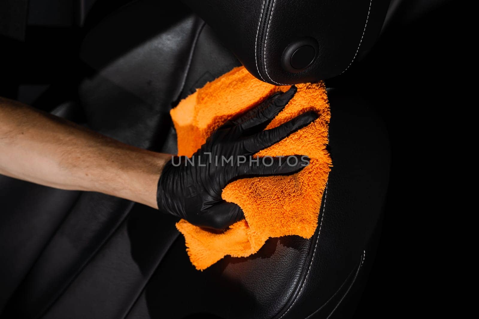 Hand car interior drying of leather seat using microfiber in detailing auto service. Cleaner worker dry car interior