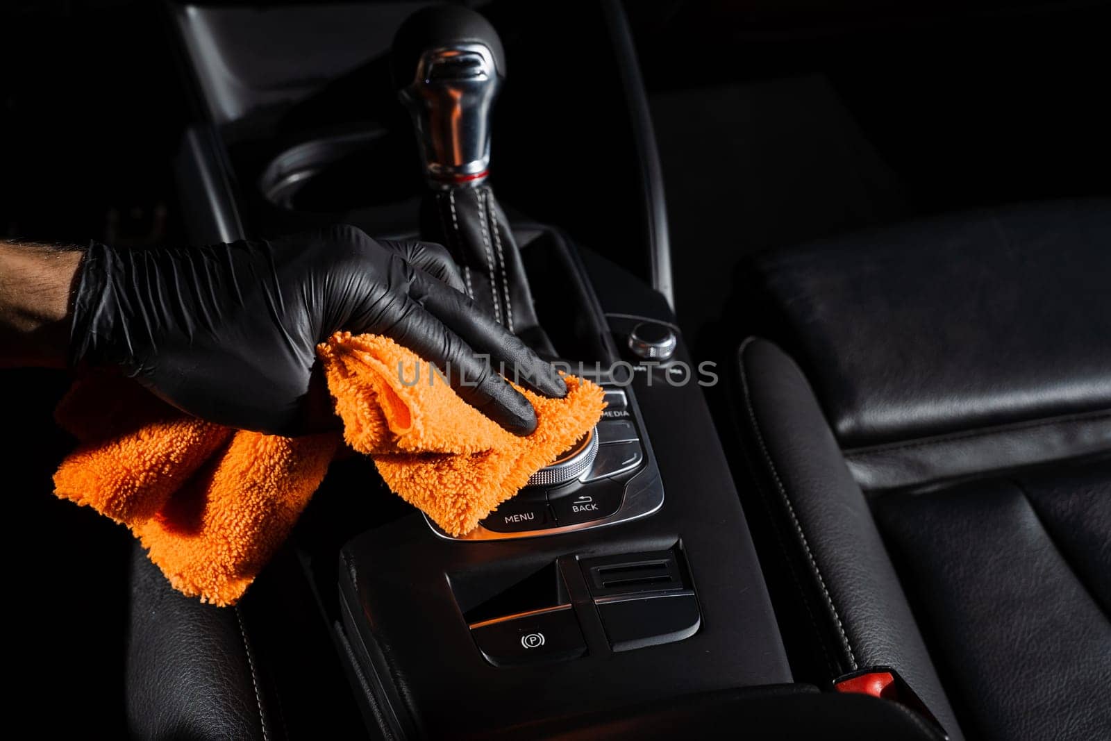 Hand car interior drying of gearbox and dashboard using microfiber in detailing auto service. Cleaner worker dry car interior