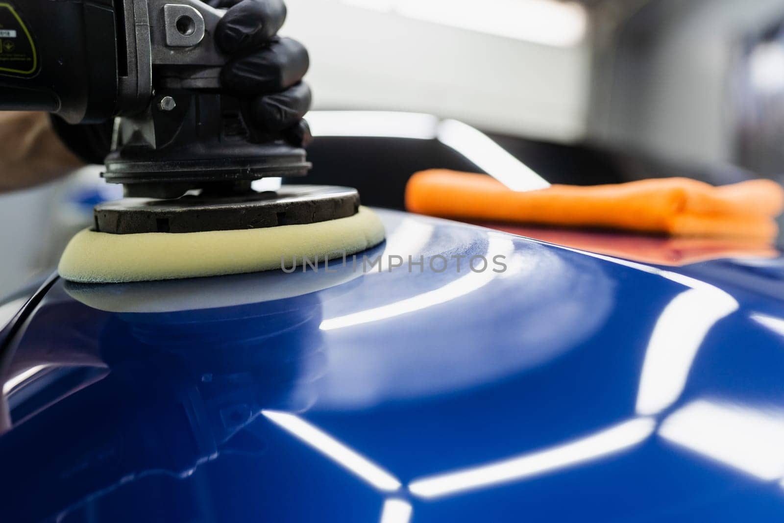 Hard wax car polishing with orbital polisher for remove scratches close-up. Working process in detailing auto service