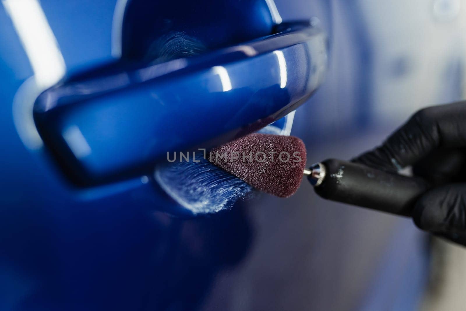 Car handle polishing with orbital polisher for remove scratches under handles of car. Worker of detailing auto service making final polishing for car
