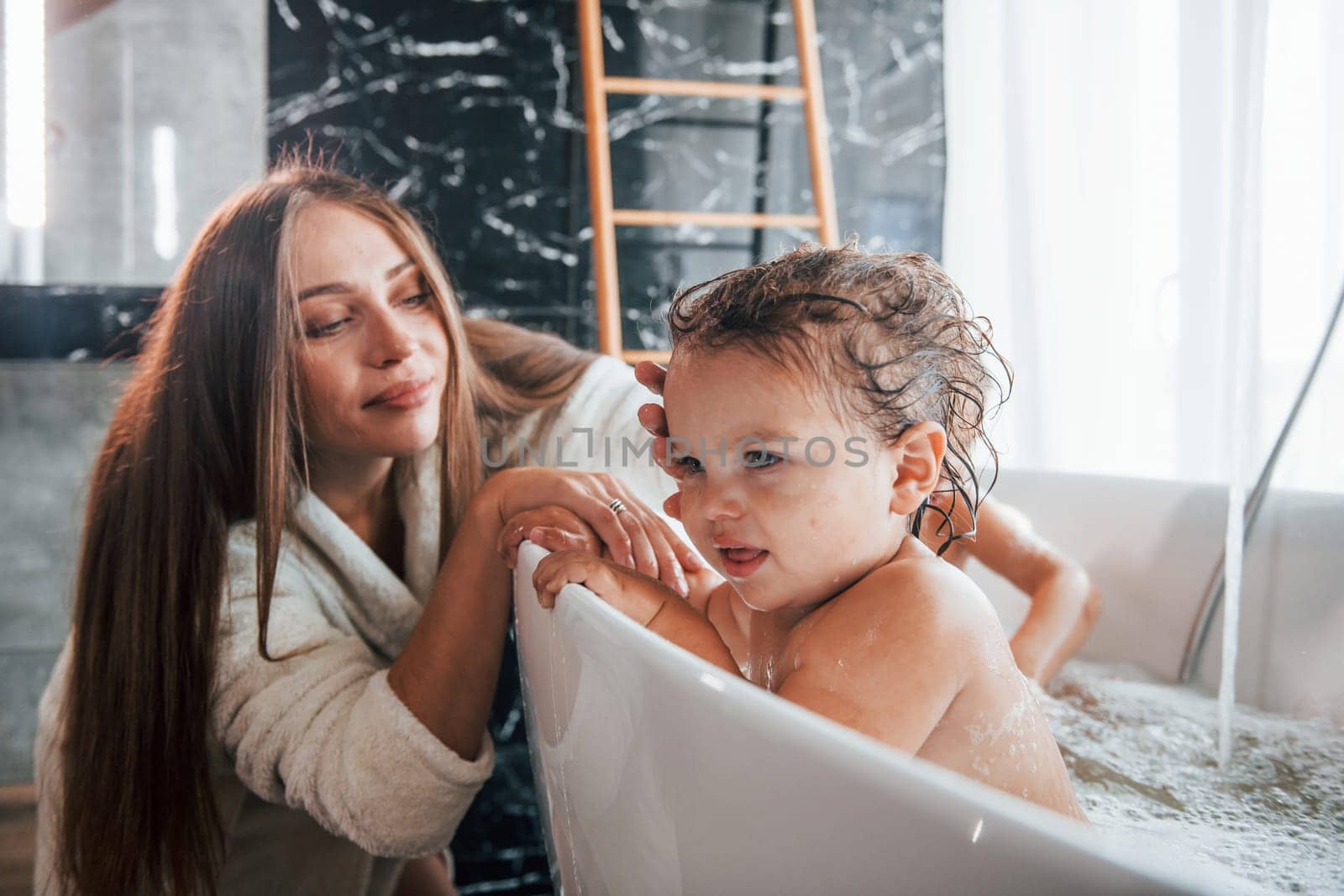 Young mother helps her son and daughter. Two kids washing in the bath by Standret