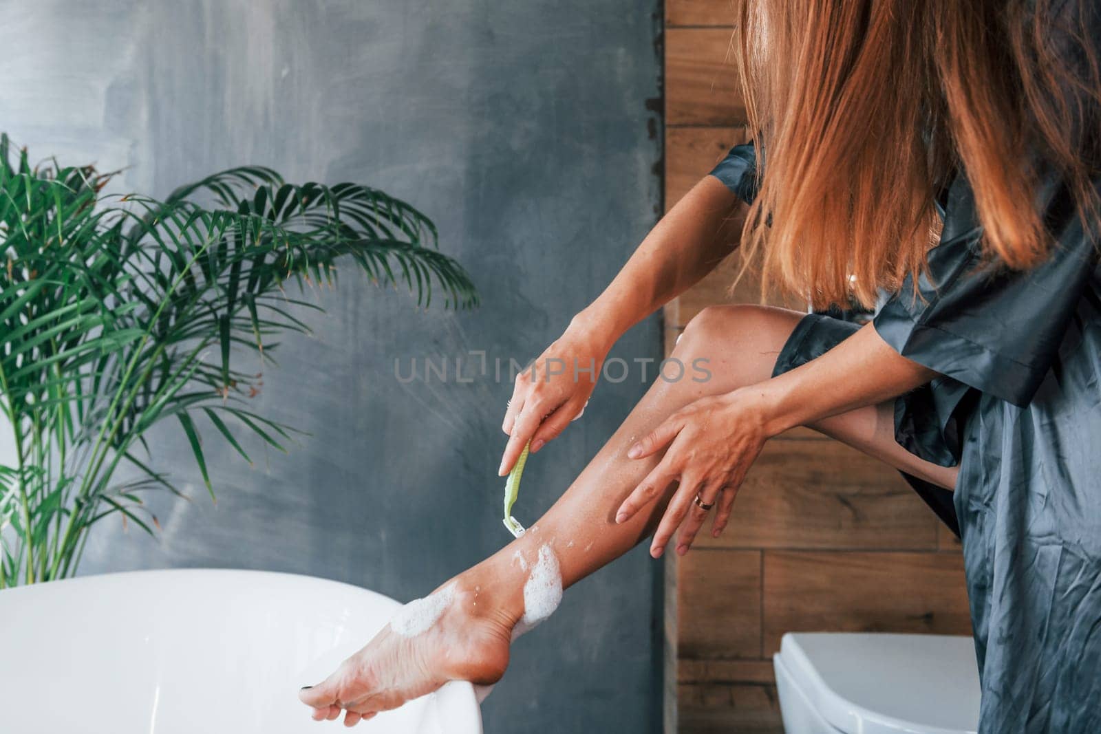 Beautiful young woman have free time at home in the bath. Shaves legs.