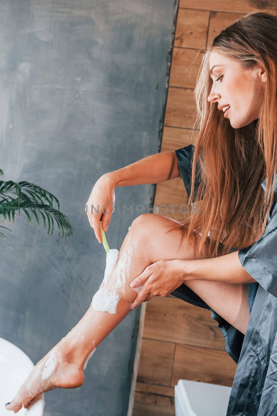 Beautiful young woman have free time at home in the bath. Shaves legs.
