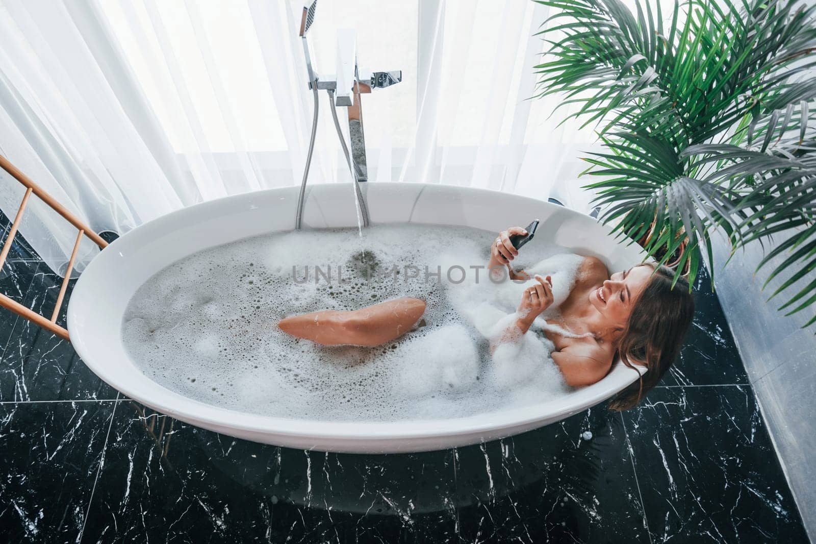 Top view. Beautiful young woman have free time at home in the bath.