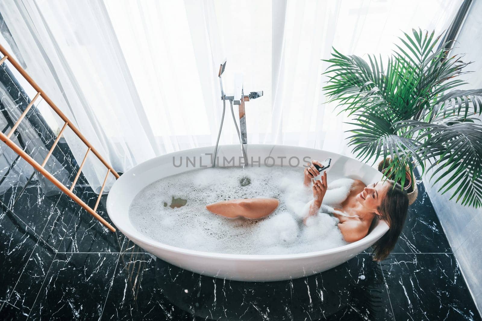 Top view. Beautiful young woman have free time at home in the bath.