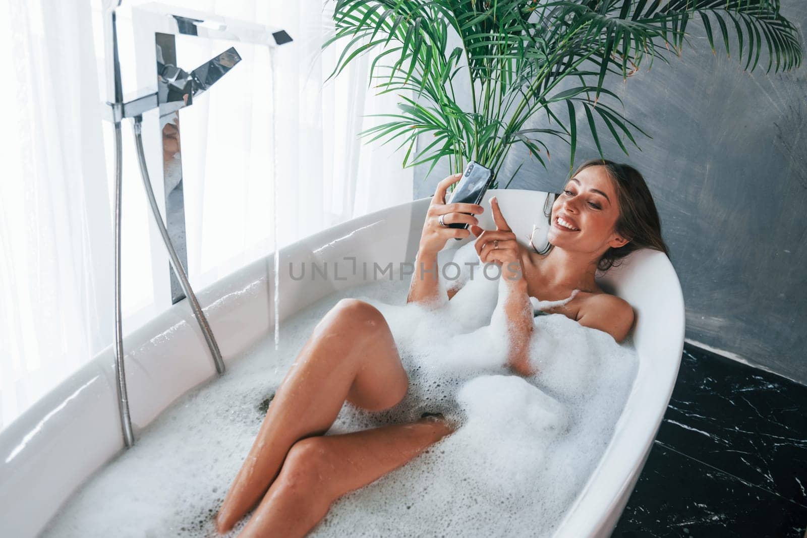 Top view. Beautiful young woman have free time at home in the bath.