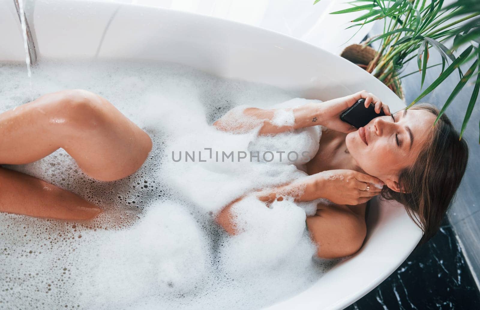 Top view. Beautiful young woman have free time at home in the bath.