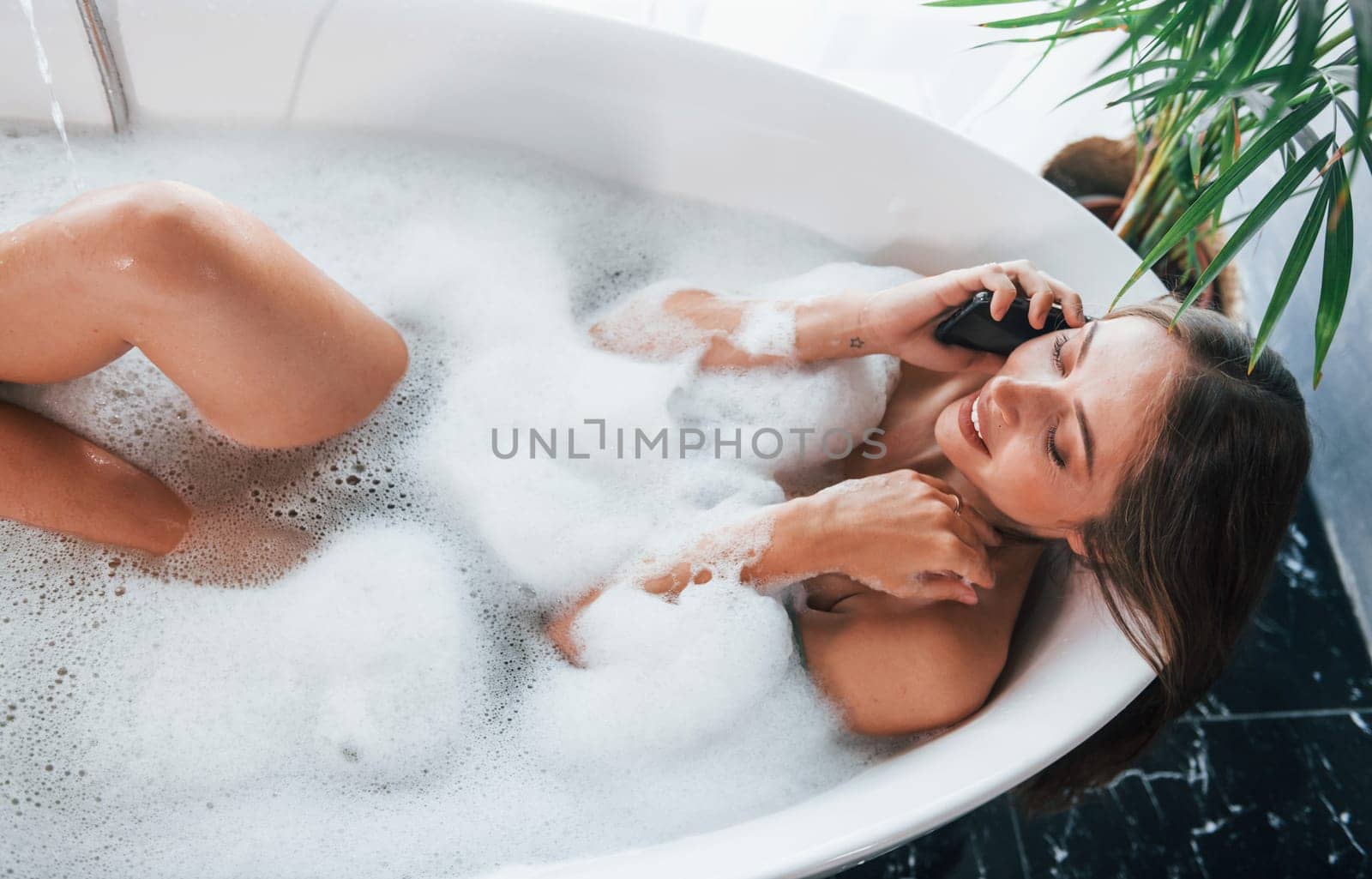 Top view. Beautiful young woman have free time at home in the bath.