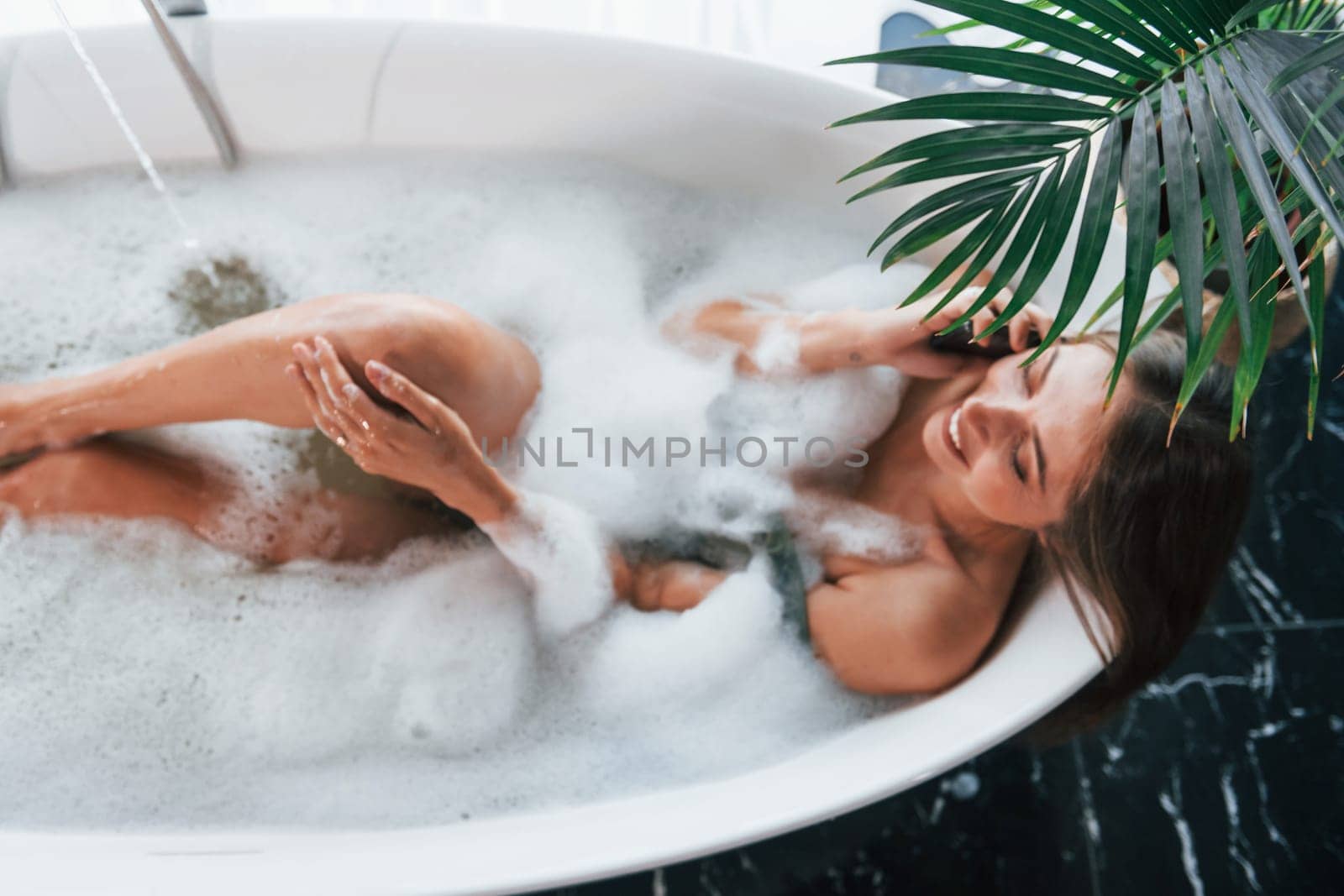 Top view. Beautiful young woman have free time at home in the bath.