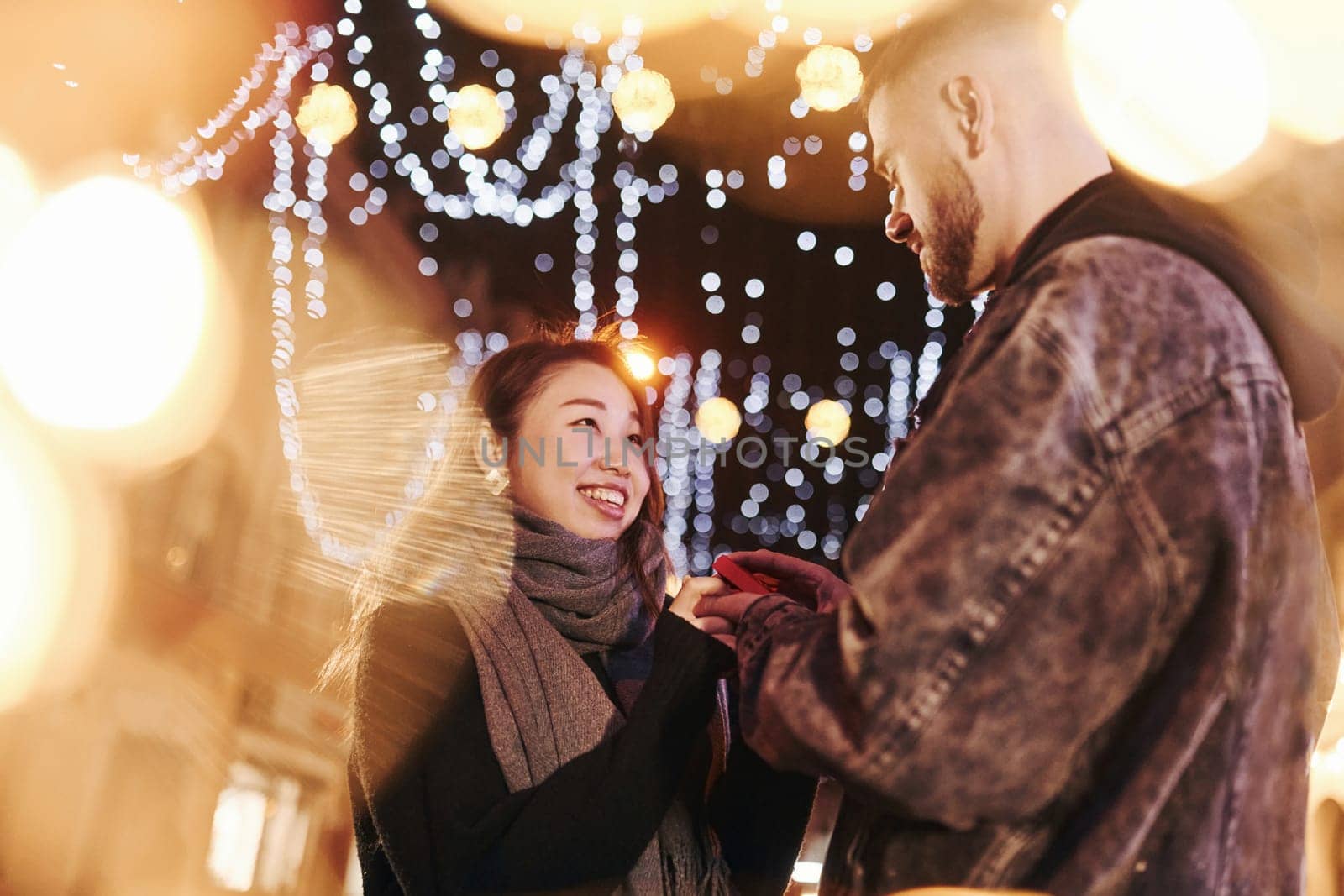 Guy doing proposal. Happy multiracial couple together outdoors in the city celebrating New year.