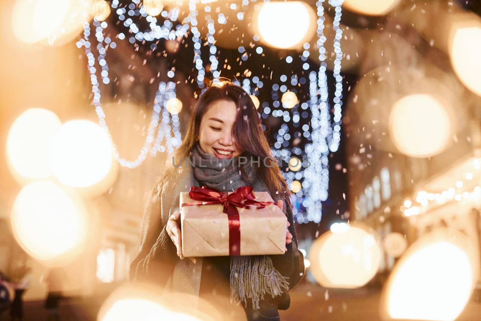 With gift box. Cute and happy asian young woman outdoors in the city celebrates New year.