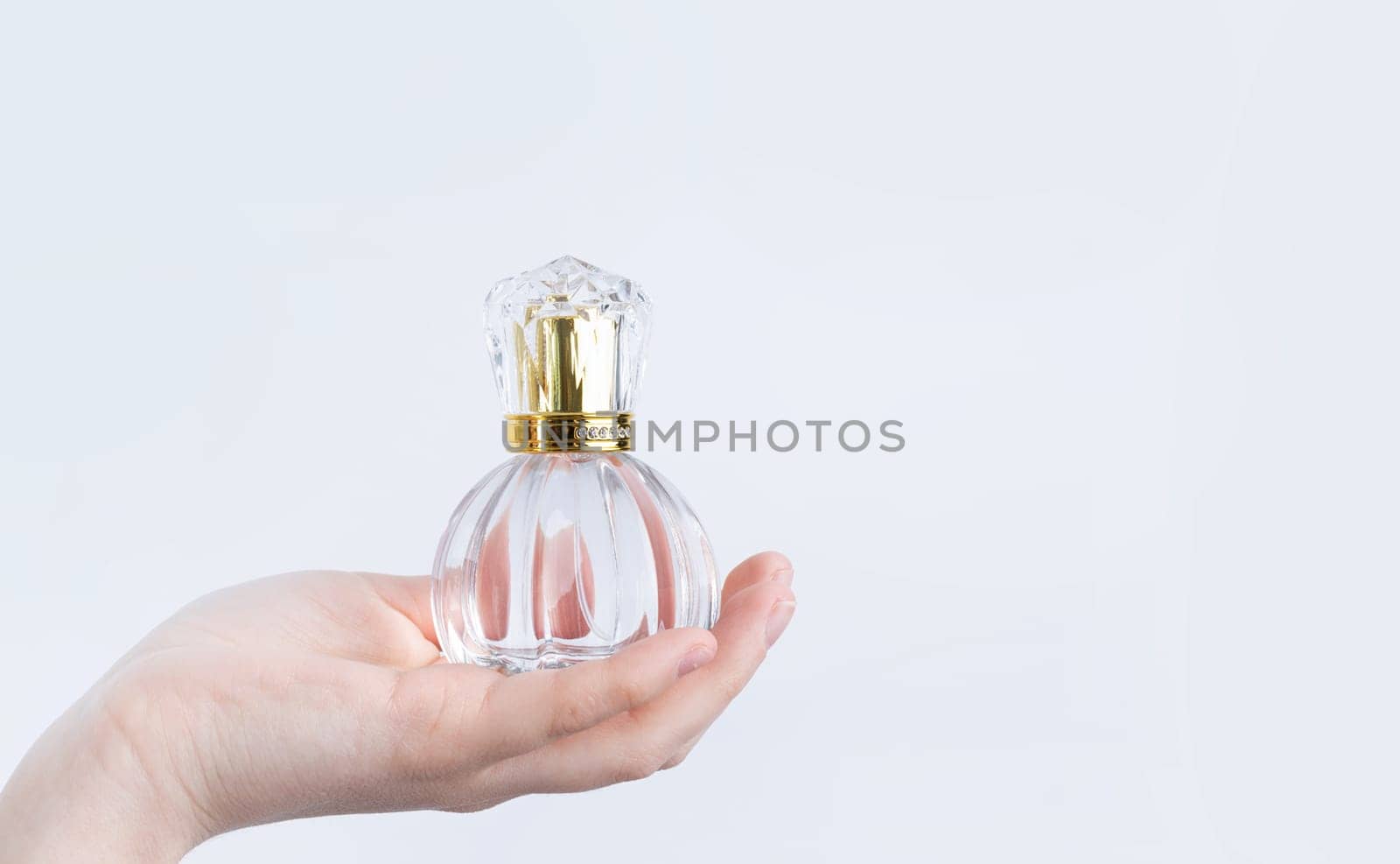 glass bottle with perfume in female hand isolated on white background by Desperada