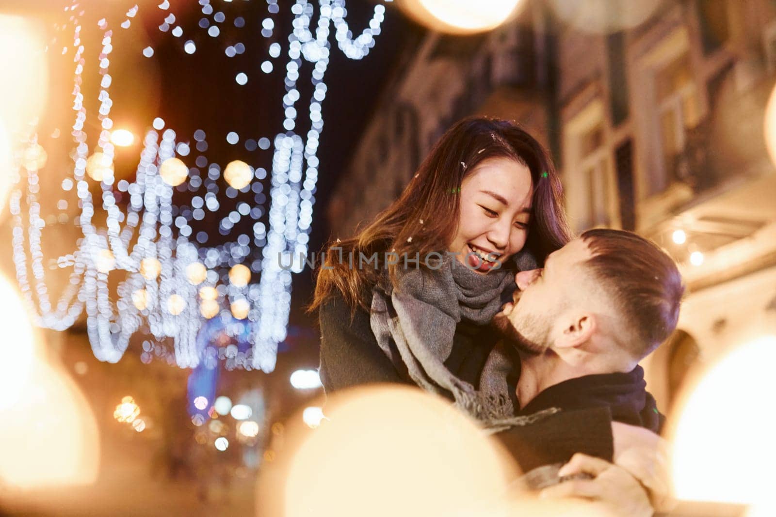 Embracing each other. Happy multiracial couple together outdoors in the city celebrating New year.