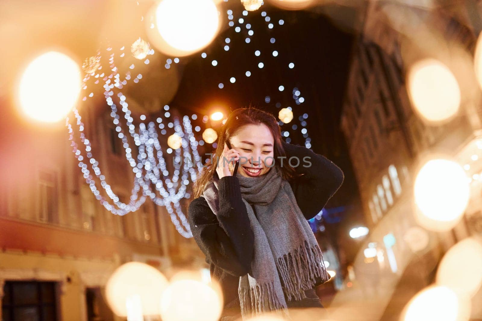 Talks by phone. Cute and happy asian young woman outdoors in the city celebrates New year.