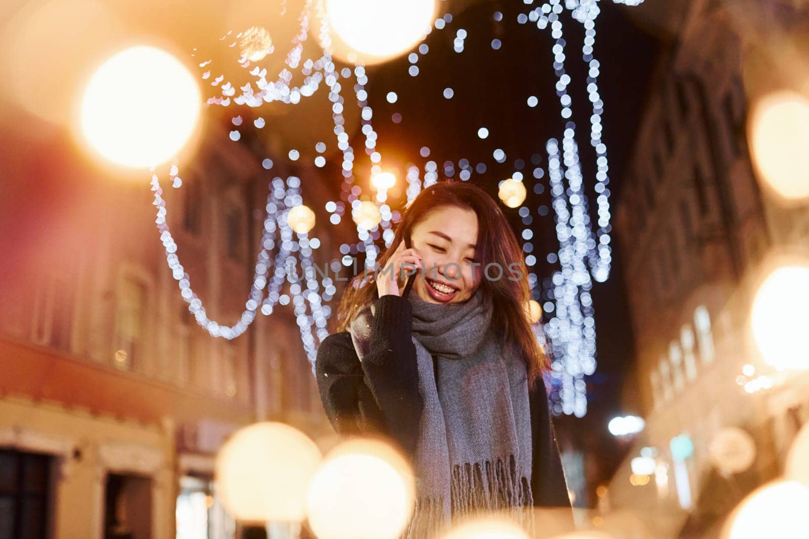 Talks by phone. Cute and happy asian young woman outdoors in the city celebrates New year.
